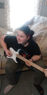 Kendelle playing the guitar at home.